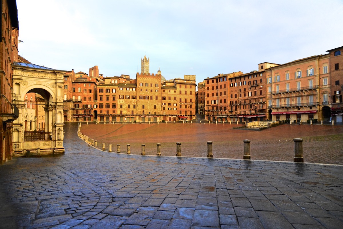 Piazza italiana rodeada de edificios medievales al amanecer.