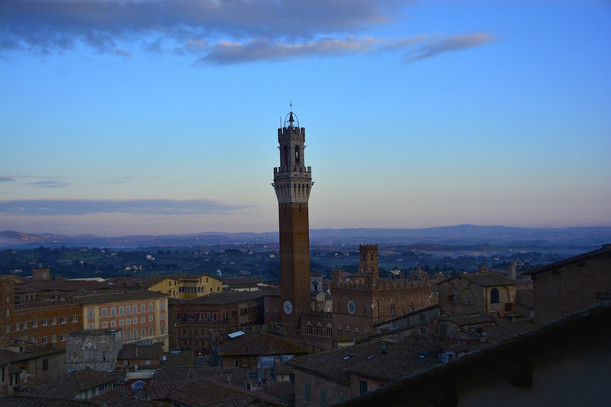 Torre alta de ladrillo sobre Siena, Italia al atardecer