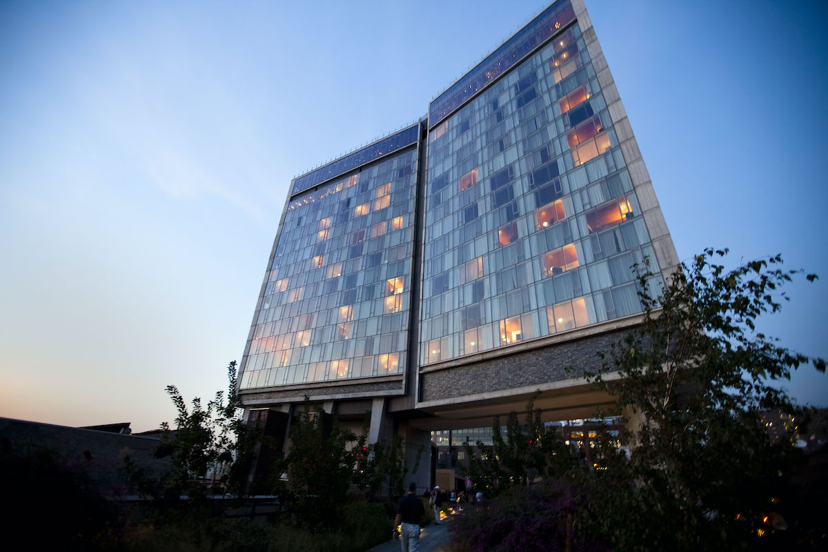 Moderno hotel de varios pisos con grandes ventanales que muestran la habitación y las luces encendidas