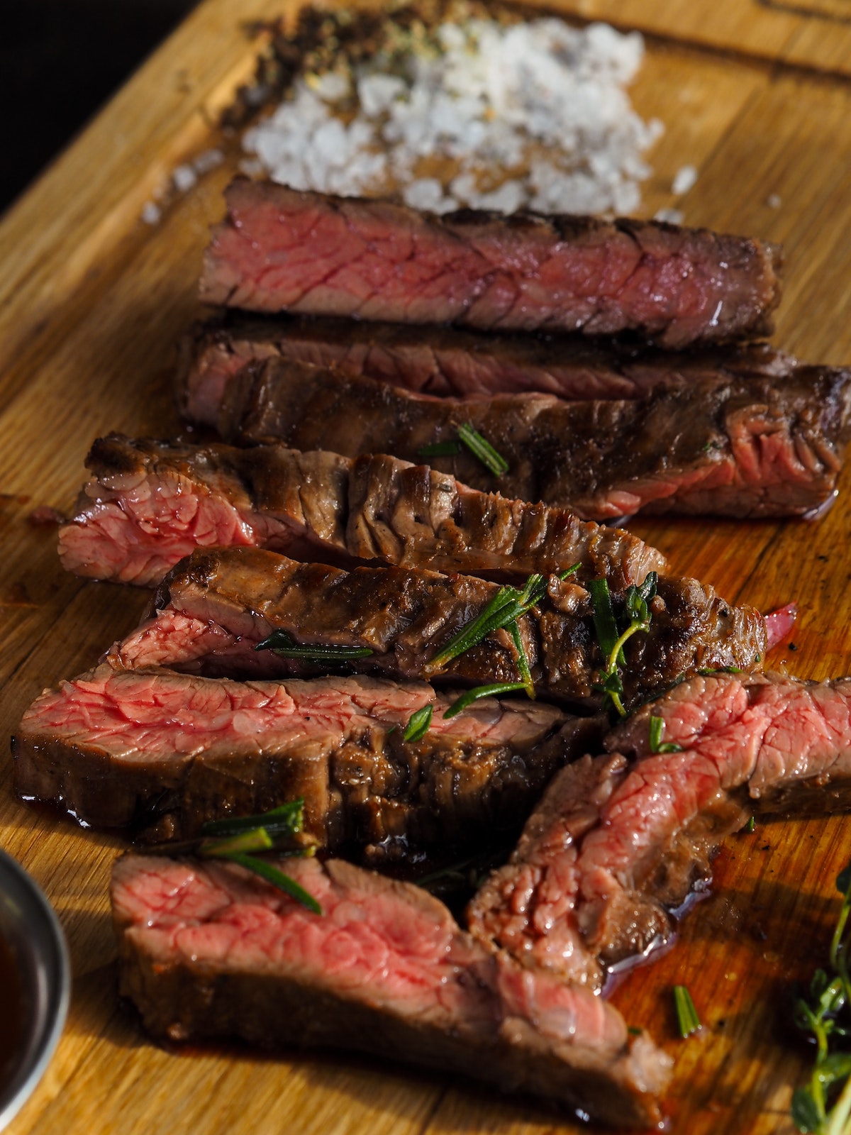 Bistec raro adornado con hierbas en una tabla de madera