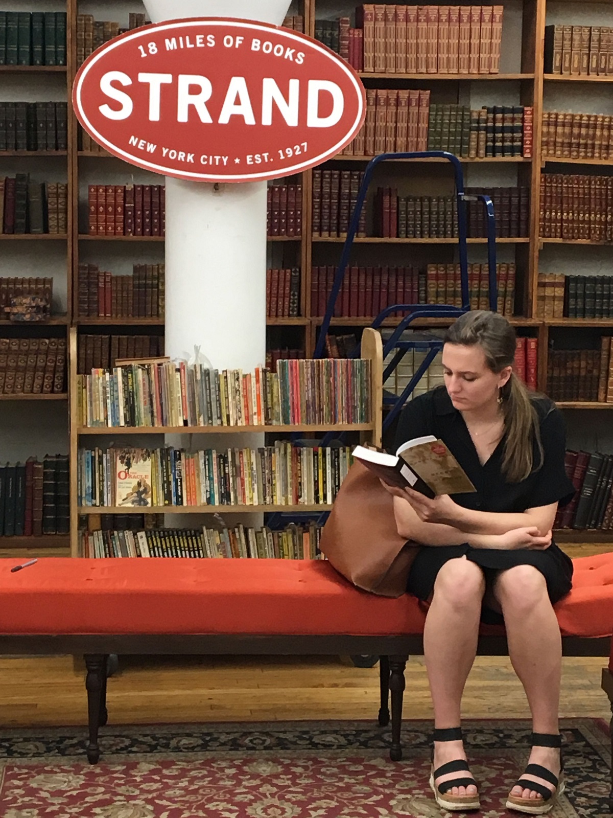 Mujer leyendo un libro en el sofá rojo de una librería