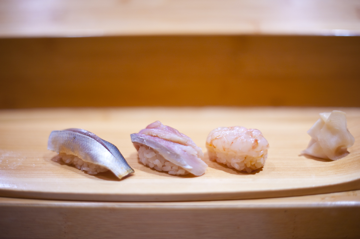 Cuatro piezas de sushi en una bandeja de madera
