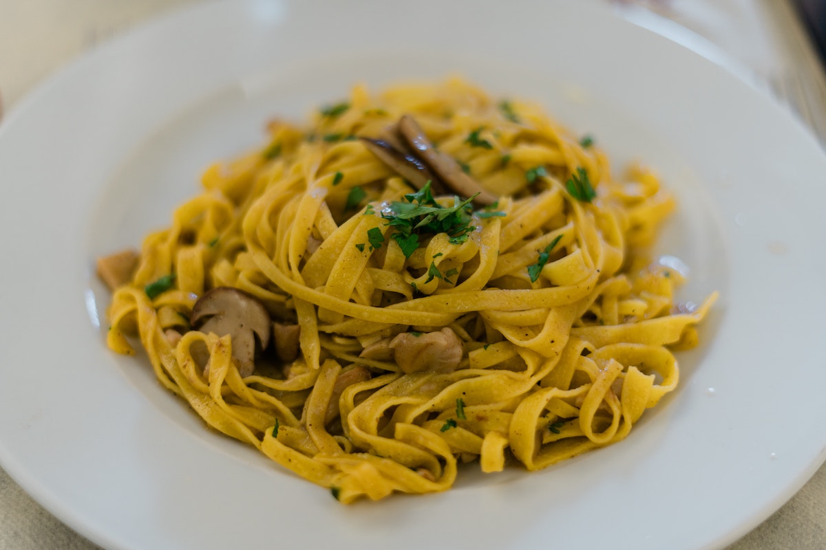 Pasta tagliatelle servida con champiñones y hierbas frescas
