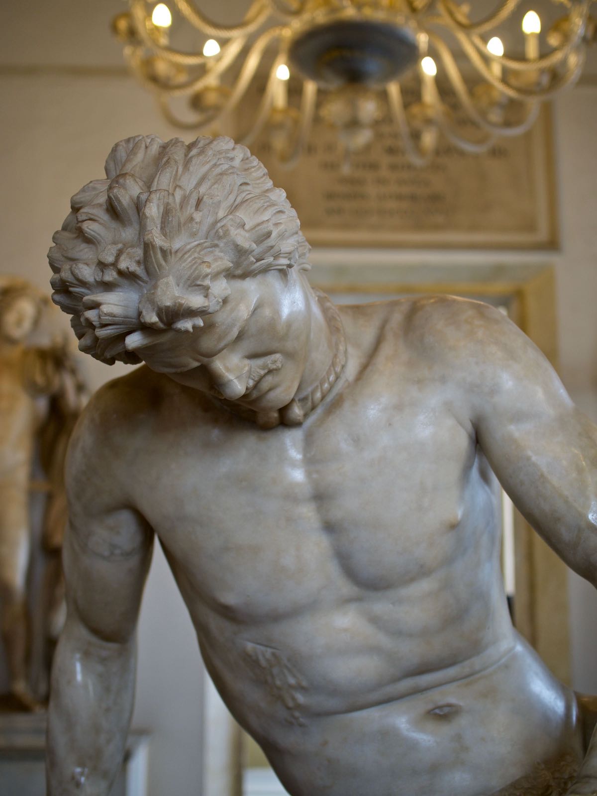 Estatua de mármol de un hombre que mira fijamente al suelo, de cintura para arriba