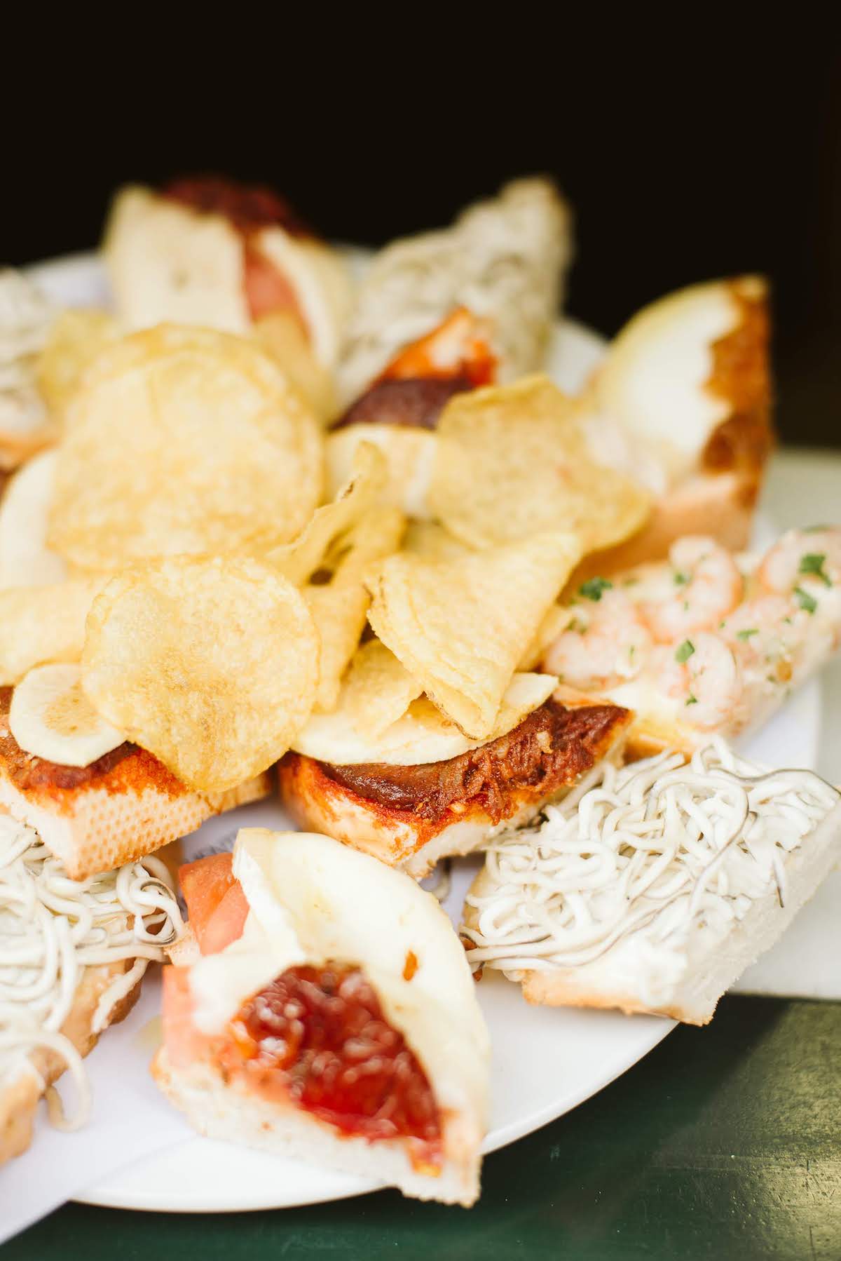 Un plato de pequeños sándwiches abiertos con varios ingredientes, con un montón de papas fritas en el medio.