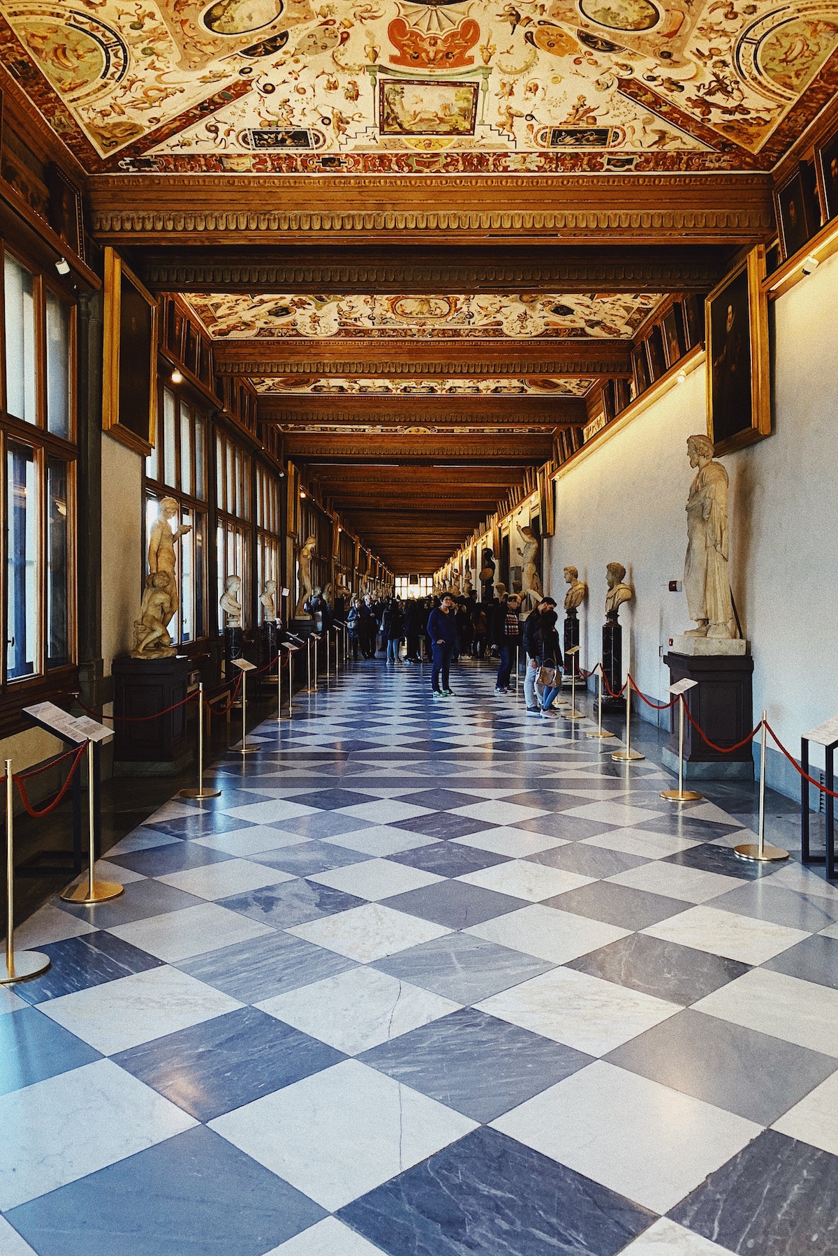 La larga sala del Museo de los Uffizi en Florencia con pisos a cuadros en blanco y negro revestidos con estatuas de mármol