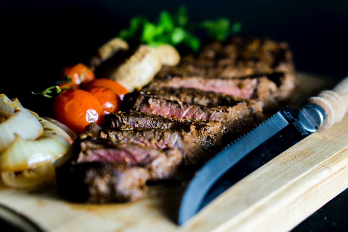 filete-con-verduras-sobre-tabla-de-madera-con-cuchillo