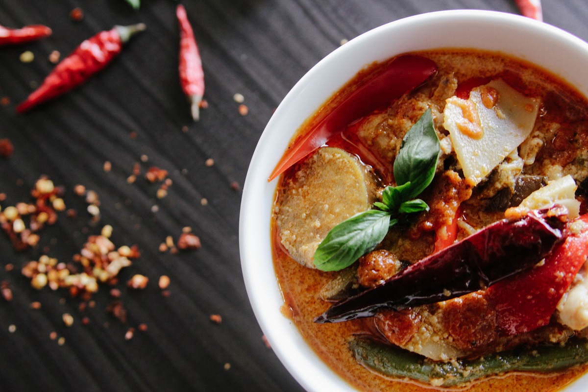 Un tazón de curry rojo acuoso con chiles y hojuelas de chile