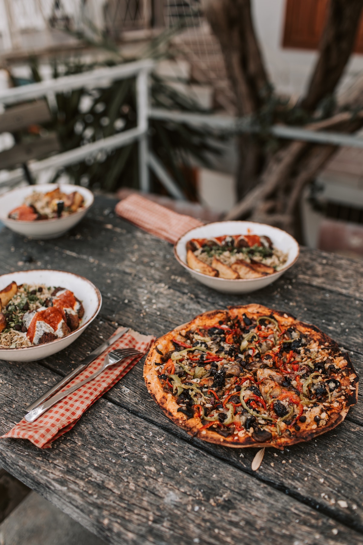 Pizza vegana y tazones de comida en una mesa de picnic de madera