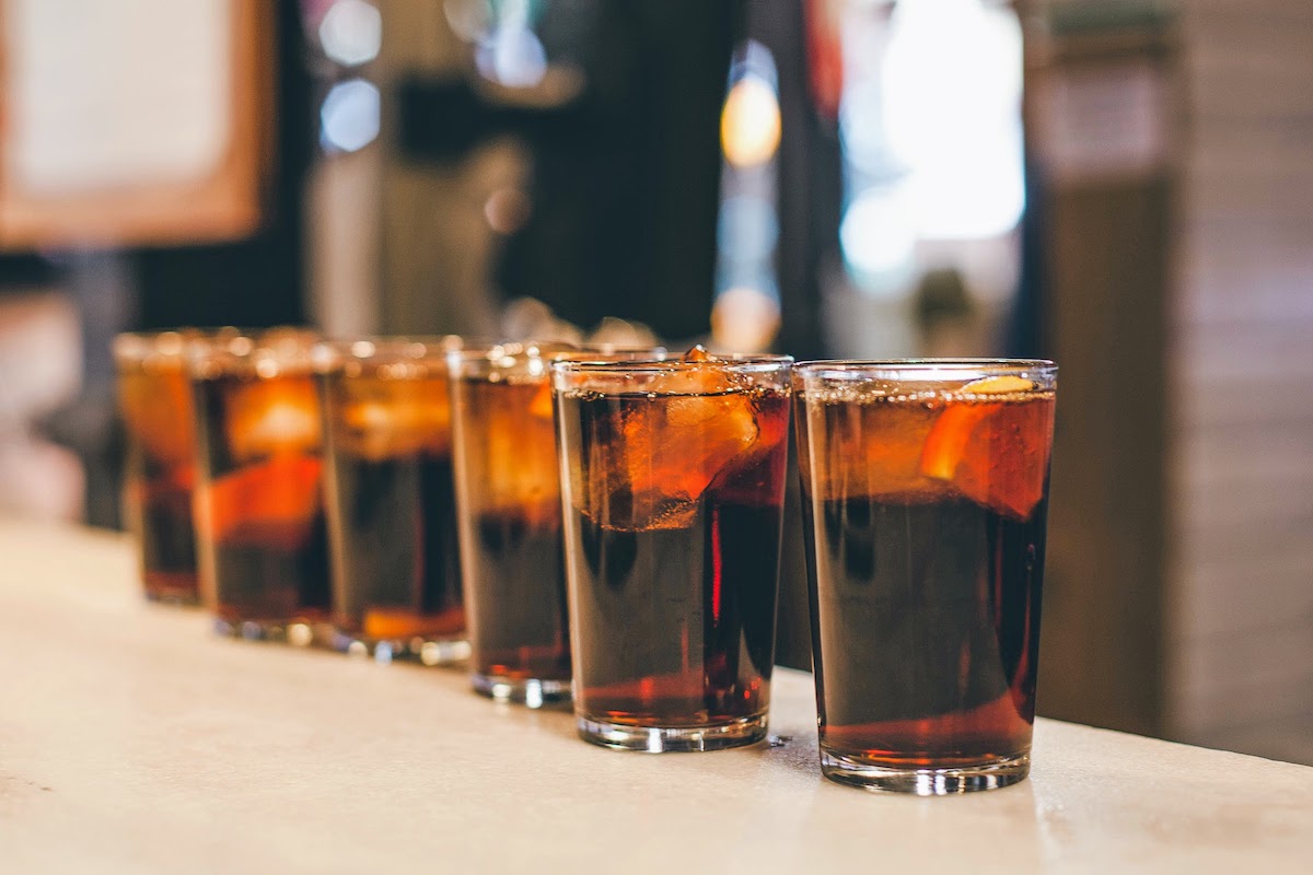 Varios vasos pequeños de vermut se alinearon encima de una barra.