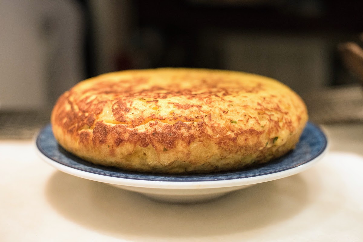 Toda una tortilla española en un plato azul y blanco.
