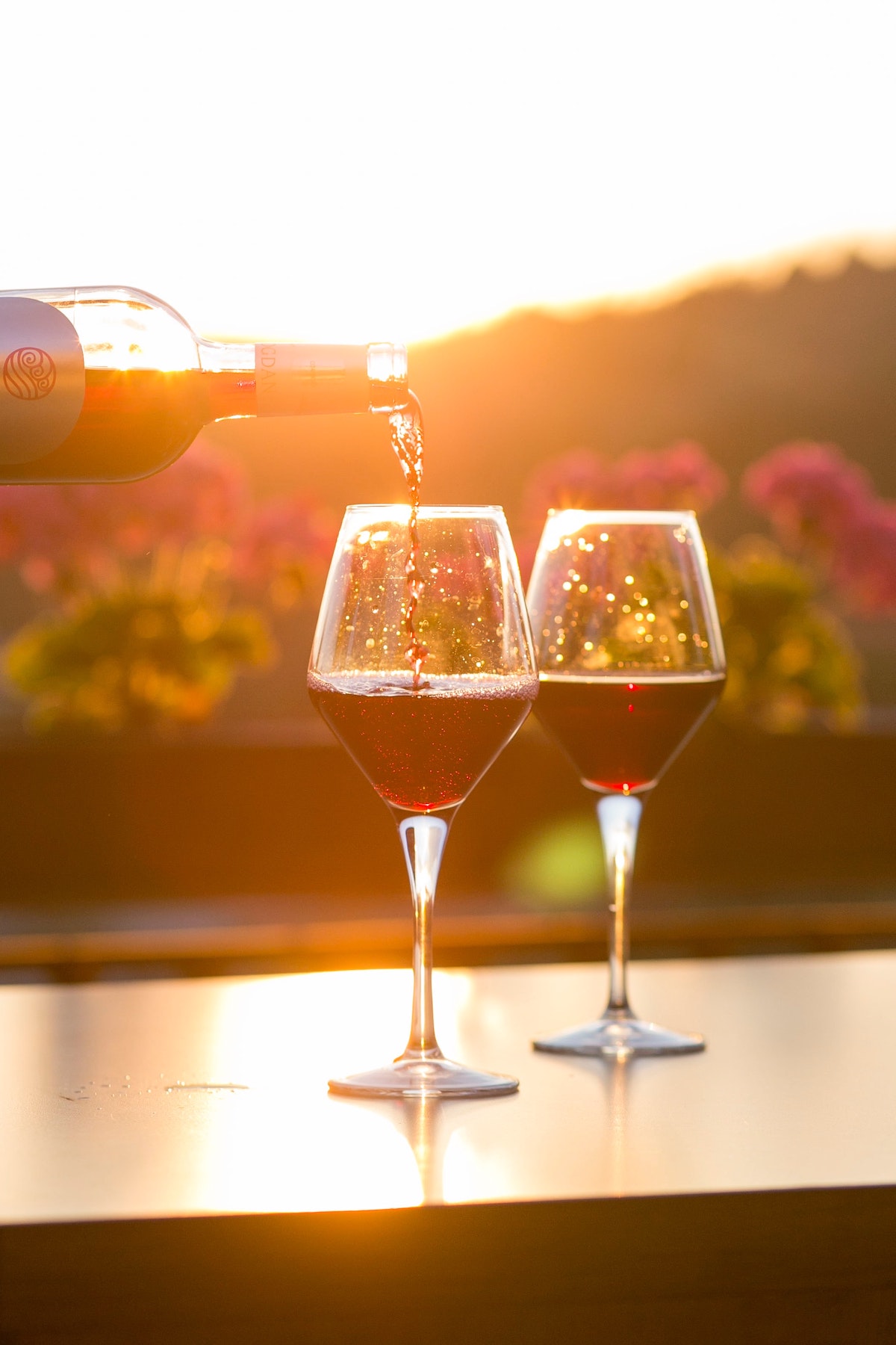 Se vierten dos copas de vino tinto al atardecer