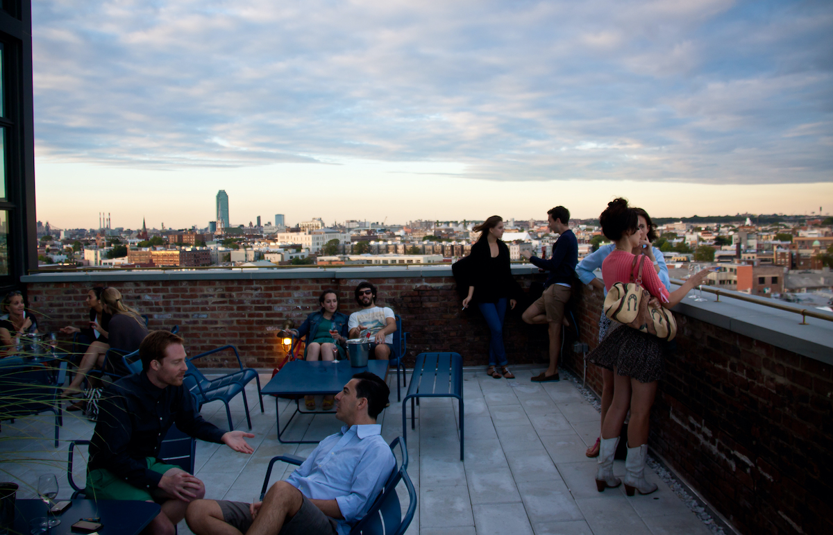 Personas en un restaurante en la azotea con vista al horizonte de Nueva York