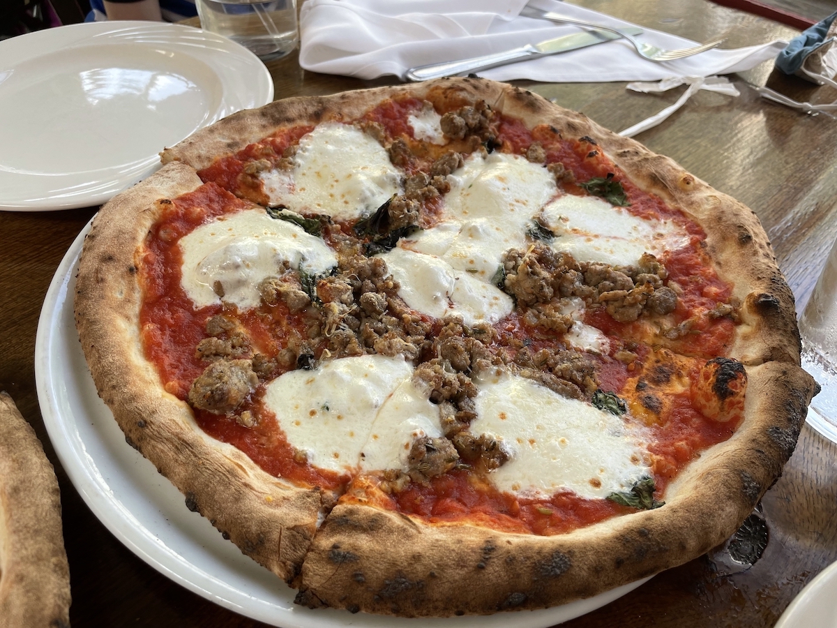 Pizza de masa gruesa con círculos de mozzarella derretida y salchicha